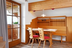 Un coin repas en bois, avec une table, des chaises et un luminaire suspendu.