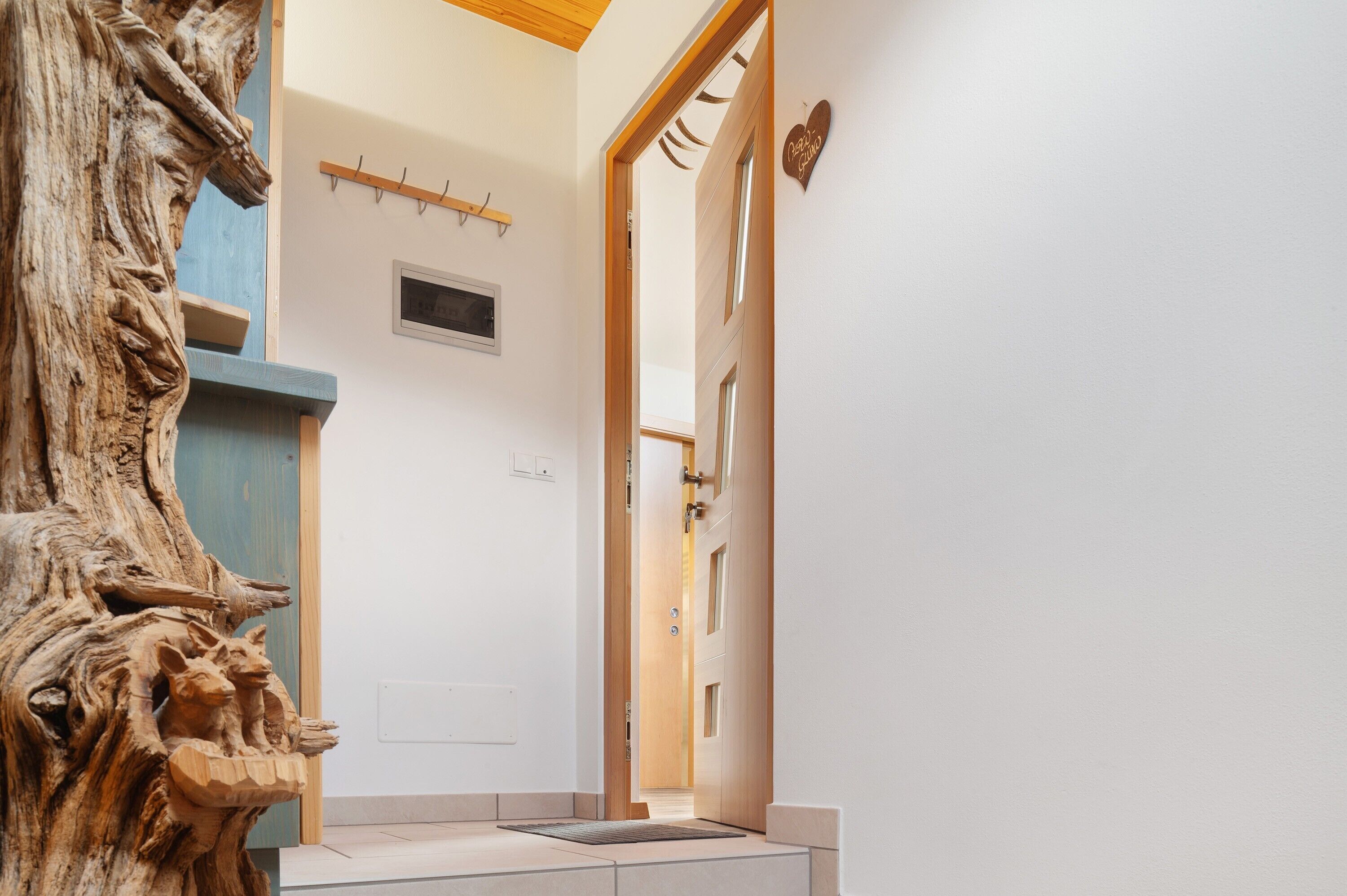 A hallway with a wooden sculpture, a door, and a heart-shaped sign.
