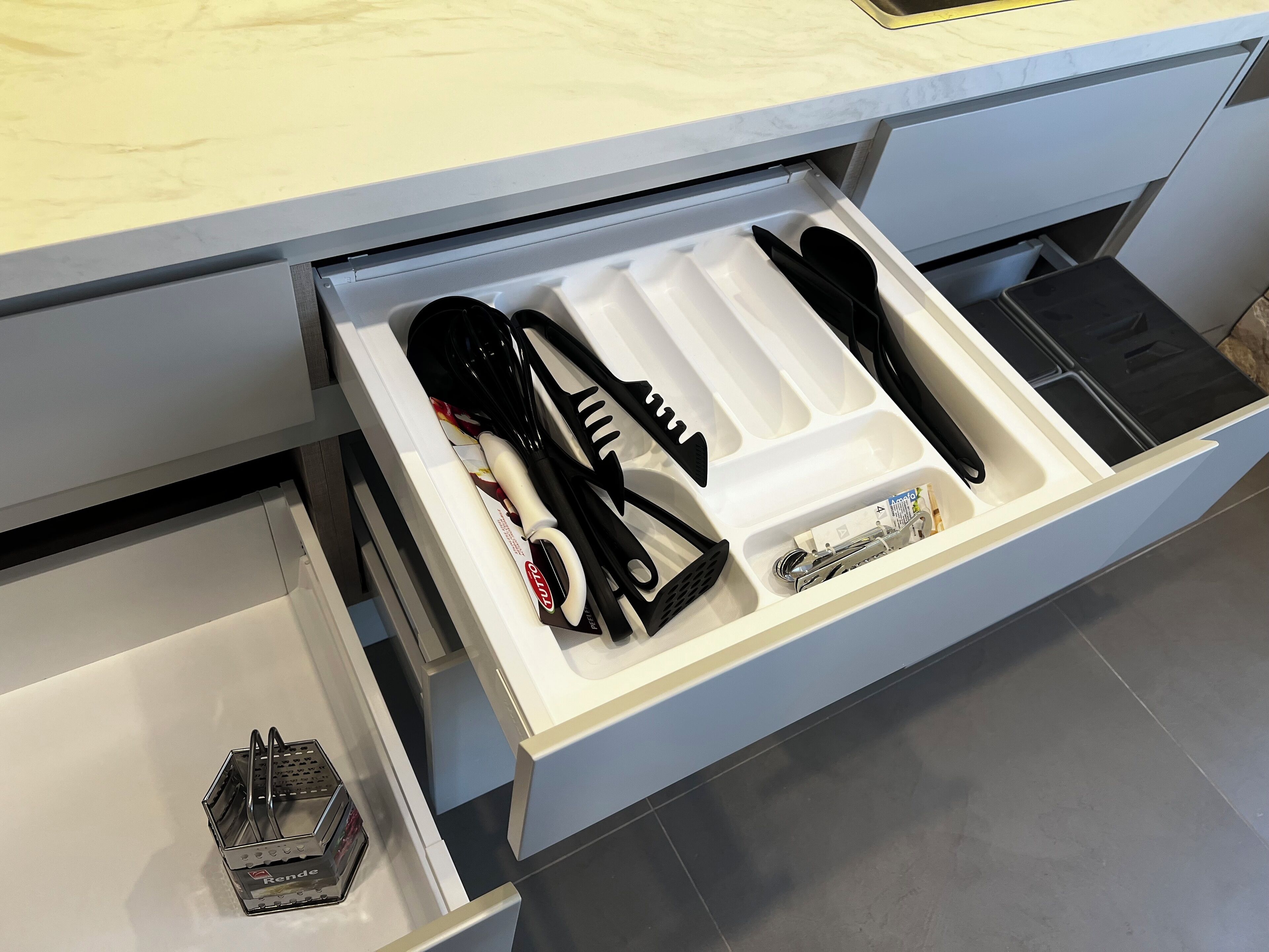 A kitchen drawer with utensils and a blender.