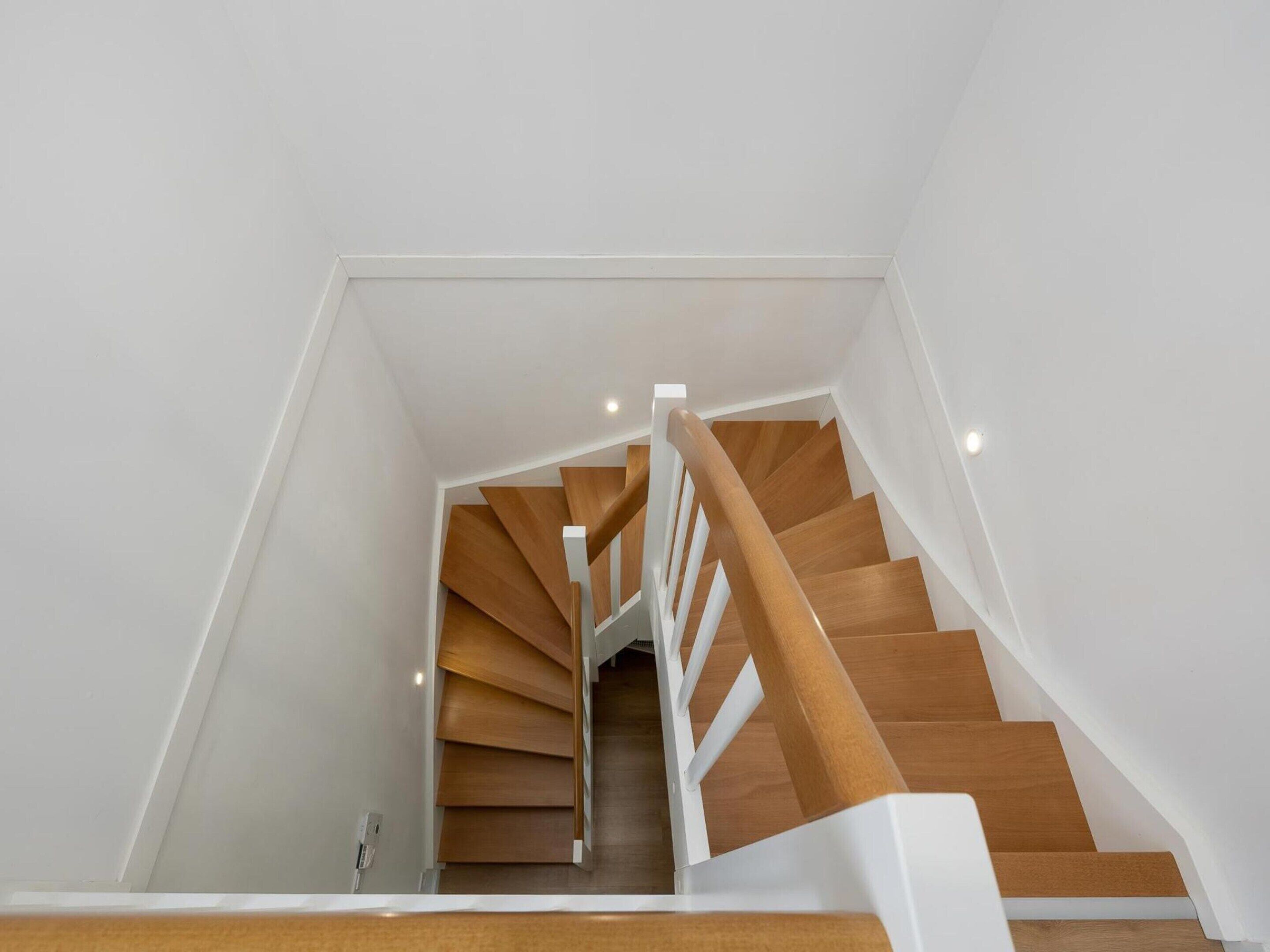 A modern staircase with wooden steps and white railings.