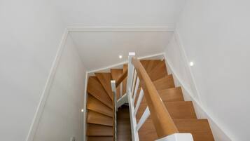 A modern staircase with wooden steps and white railings.