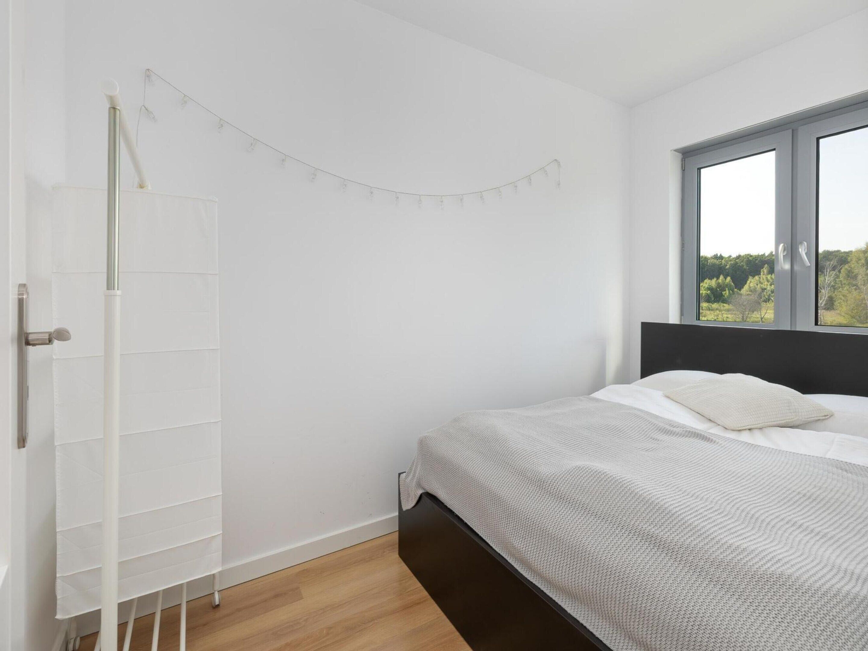 Ein Schlafzimmer mit Bett, Fenster mit Blick und weißer Wand.