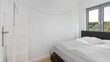 Ein Schlafzimmer mit Bett, Fenster mit Blick und weißer Wand.