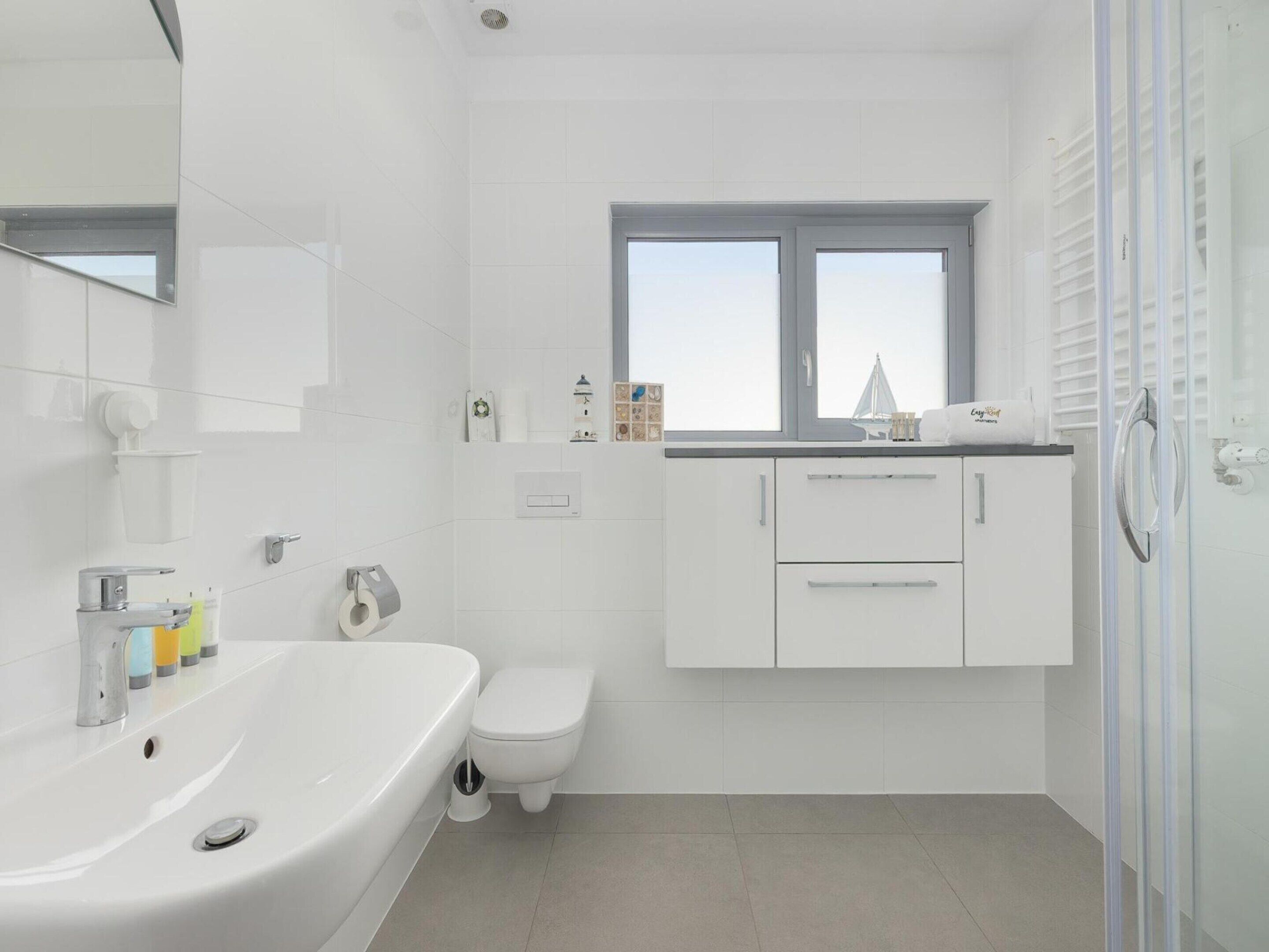 A modern bathroom with a bathtub, toilet, and a window.