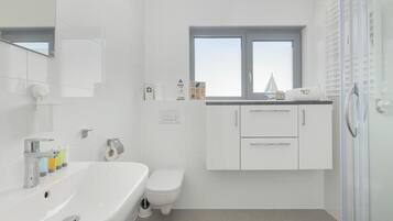 A modern bathroom with a bathtub, toilet, and a window.