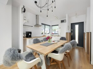 Una cocina moderna con comedor, muebles blancos, una cafetera y un reloj de marco negro.