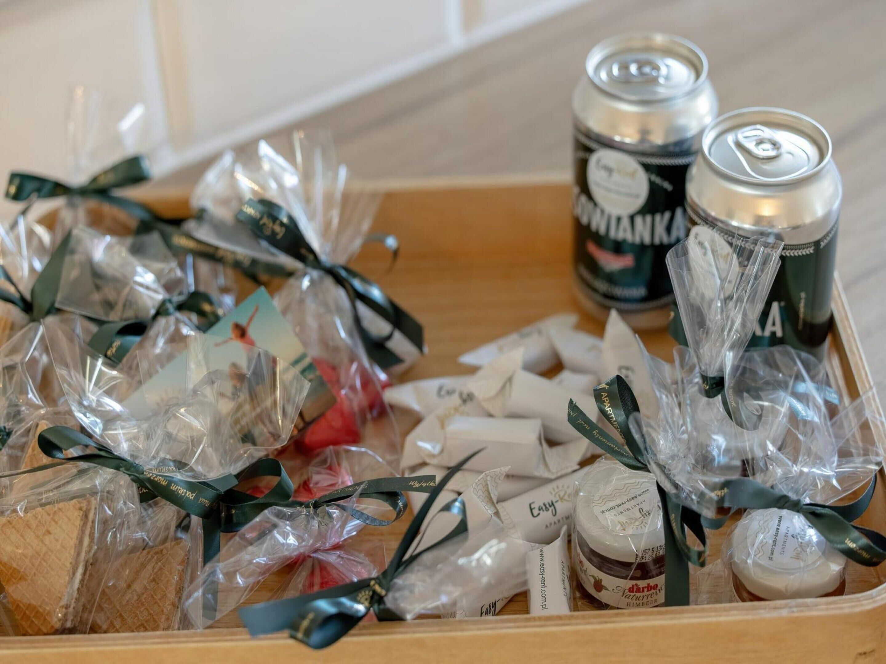 A wooden tray containing various packaged food items, including bread, jams, and a can of beer.