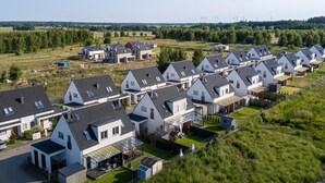 A residential area with modern houses, a clear sky, and wind turbines in the distance.