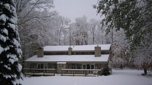 Een groot, twee verdiepingen tellend gebouw met een symmetrische gevel, omgeven door met sneeuw bedekte bomen.