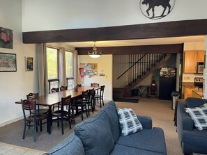 Ein modernes Wohnzimmer mit Essbereich, einer Treppe und einer Küche.
