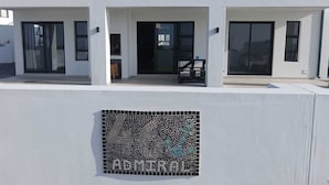 A modern building with a balcony, large windows, and a mosaic sign reading "40 ADMIRAL".