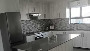 A modern kitchen with a large island, stainless steel appliances, and a tiled backsplash.