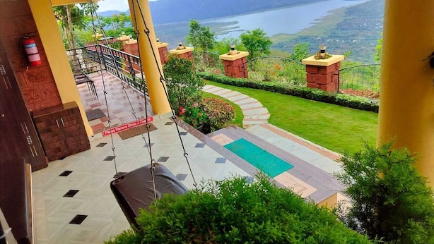 Un balcón con vista a un lago y montañas, un área de piscina y un extintor.