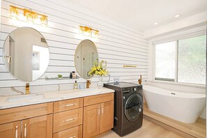 Ein modernes Badezimmer mit einem großen Spiegel, einer Waschmaschine und einer Badewanne.