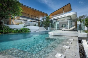 A modern house with a glass-enclosed pool area, a wooden deck, and a staircase leading to an upper level. - Villa Zavaya Luxury Retreat With Pool (Choeng Thale)