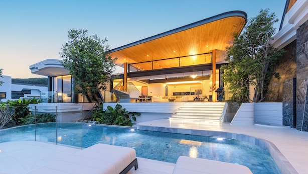 Une maison moderne dotée d’une piscine, d’un espace salon extérieur et d’un escalier menant à l’étage supérieur.