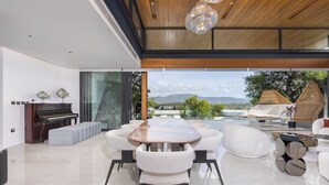 Un salon moderne avec un piano, une table à manger en bois et une vue sur les montagnes.