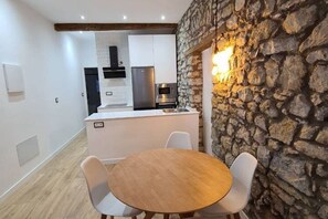 Une cuisine moderne avec des armoires blanches, un four encastré et un mur en pierre agrémenté d’un luminaire.
