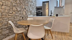 Una cocina moderna con una pared de piedra, una mesa redonda de madera y cuatro sillas blancas.