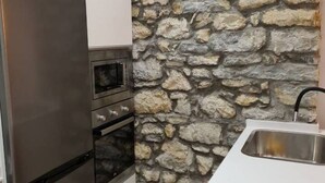Una cocina con pared de piedra, horno de acero inoxidable y un lavamanos.