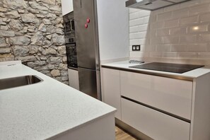 A kitchen with a stone wall, stainless steel appliances, and a white countertop.