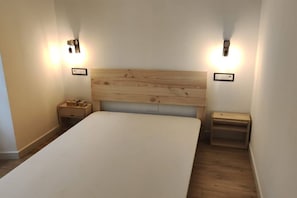 A bedroom with a wooden headboard, two bedside tables, and wall-mounted lights.
