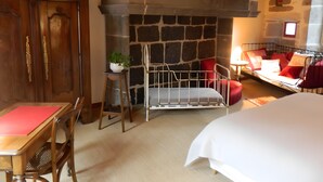A room with a stone fireplace, a bed, a desk with a chair, and a small table with a plant. - La Maison De Marie: Renaissance-Style Holiday Home with Private Terrace and Wi-Fi (Murat)