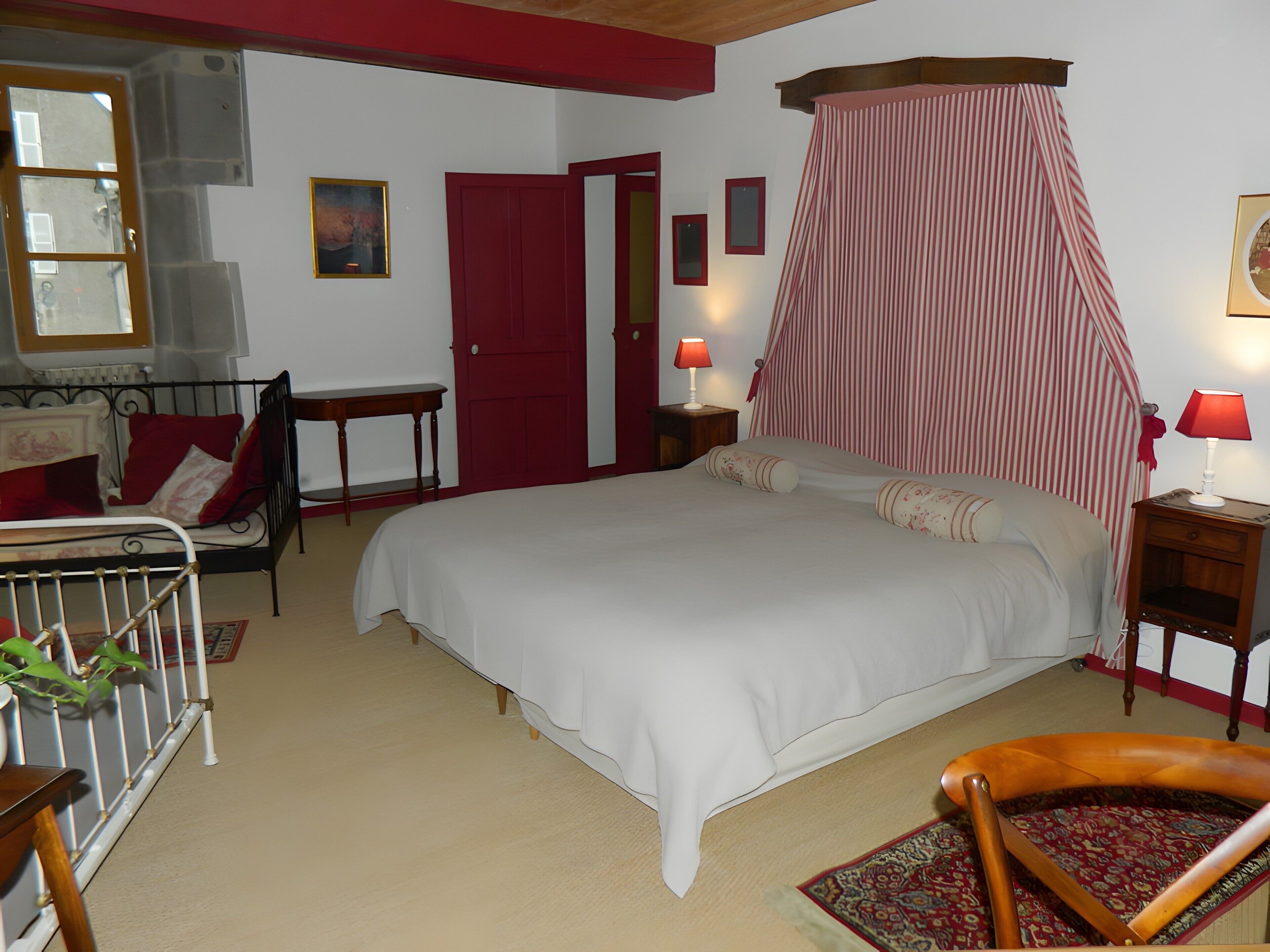 Ein Schlafzimmer mit Bett, Stuhl, Nachttisch, Lampe und Fenster.