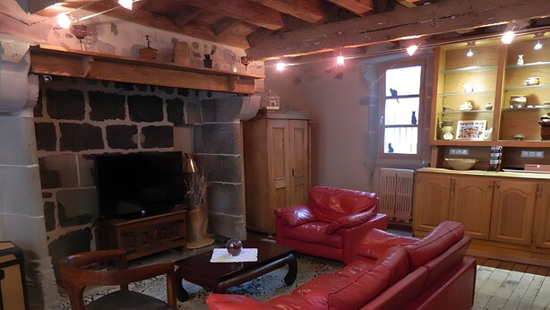 A living room with a stone fireplace, a red leather sofa, a wooden coffee table, and a television. - La Maison De Marie: Renaissance-Style Holiday Home with Private Terrace and Wi-Fi (Murat)