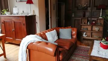 Een woonkamer met een leren bank, een houten kast, een rode lamp en een kamerkleed met dessin.