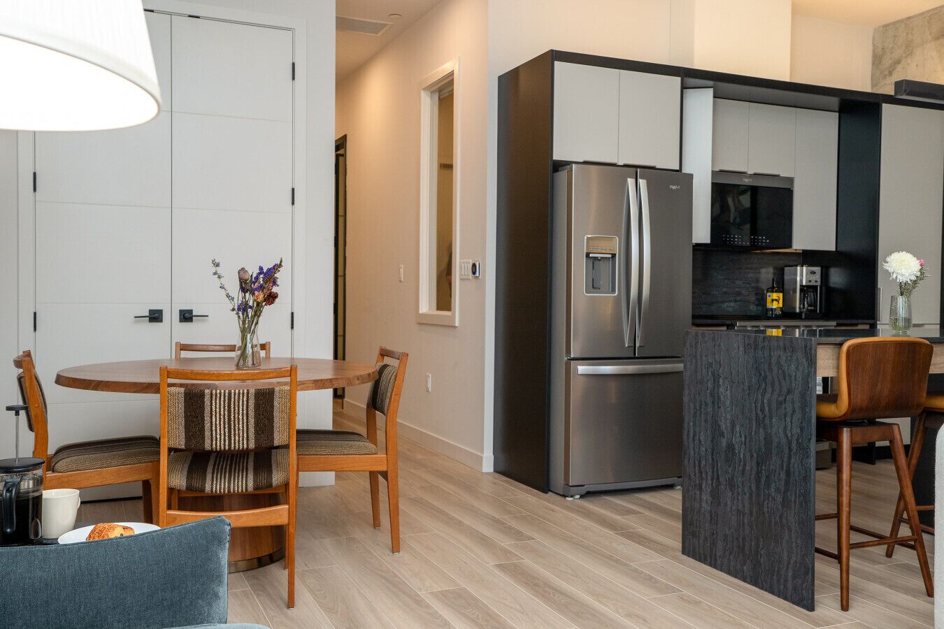 Una cocina moderna con un refrigerador de acero inoxidable, una cafetera y una pequeña isla con asientos.
