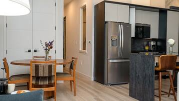 Una cocina moderna con un refrigerador de acero inoxidable, una cafetera y una pequeña isla con asientos.