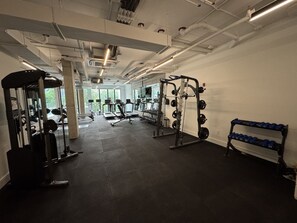 A gym with various exercise equipment, including weight machines and free weights, and a rack of dumbbells.