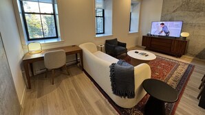 A modern living room with a sofa, a coffee table, a TV, and a desk with a chair. - Mid-Century Modern 2B/1B (Halifax)