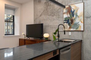 A modern kitchen with a flat-screen TV, a pendant light, and a sink. - *NEW Mid-Century Modern 2B/1B (Halifax)