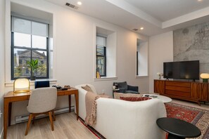 A modern living room with a sofa, a coffee table, a TV, and a dining area with a table and chairs.