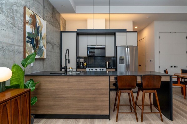 A modern kitchen with a central island, bar stools, and a dining table. - *NEW Mid-Century Modern 2B/1B (Halifax)