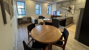 A modern kitchen with a wooden dining table, built-in appliances, and large windows. - Mid-Century Modern 2B/1B (Halifax)