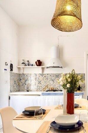 A modern kitchen with a hanging light fixture, a white gas stove, and a tiled backsplash.