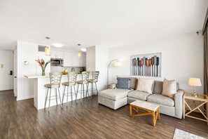 Ein modernes Wohnzimmer mit Ecksofa, Couchtisch und einer Essecke mit Barhocker.