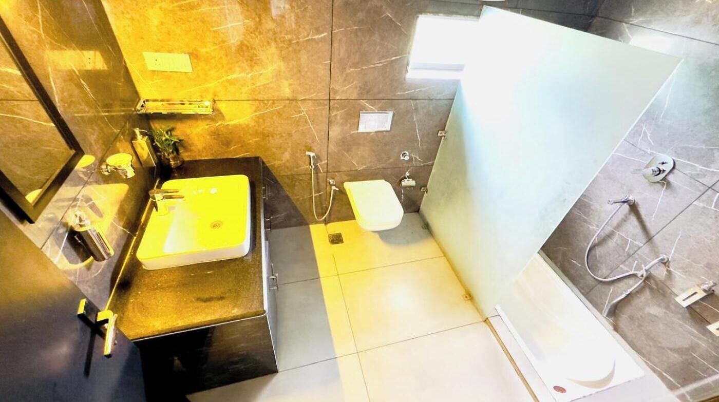 A modern bathroom with a black sink, a mirror, and a shower area.