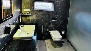 Une salle de bain moderne avec un mur en marbre, un lavabo, des toilettes et une fenêtre.