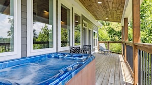 A hot tub on a wooden deck with a covered area, large windows, and outdoor furniture. - Amazing Views Hot Tub Arcade Firepit (Gatlinburg)