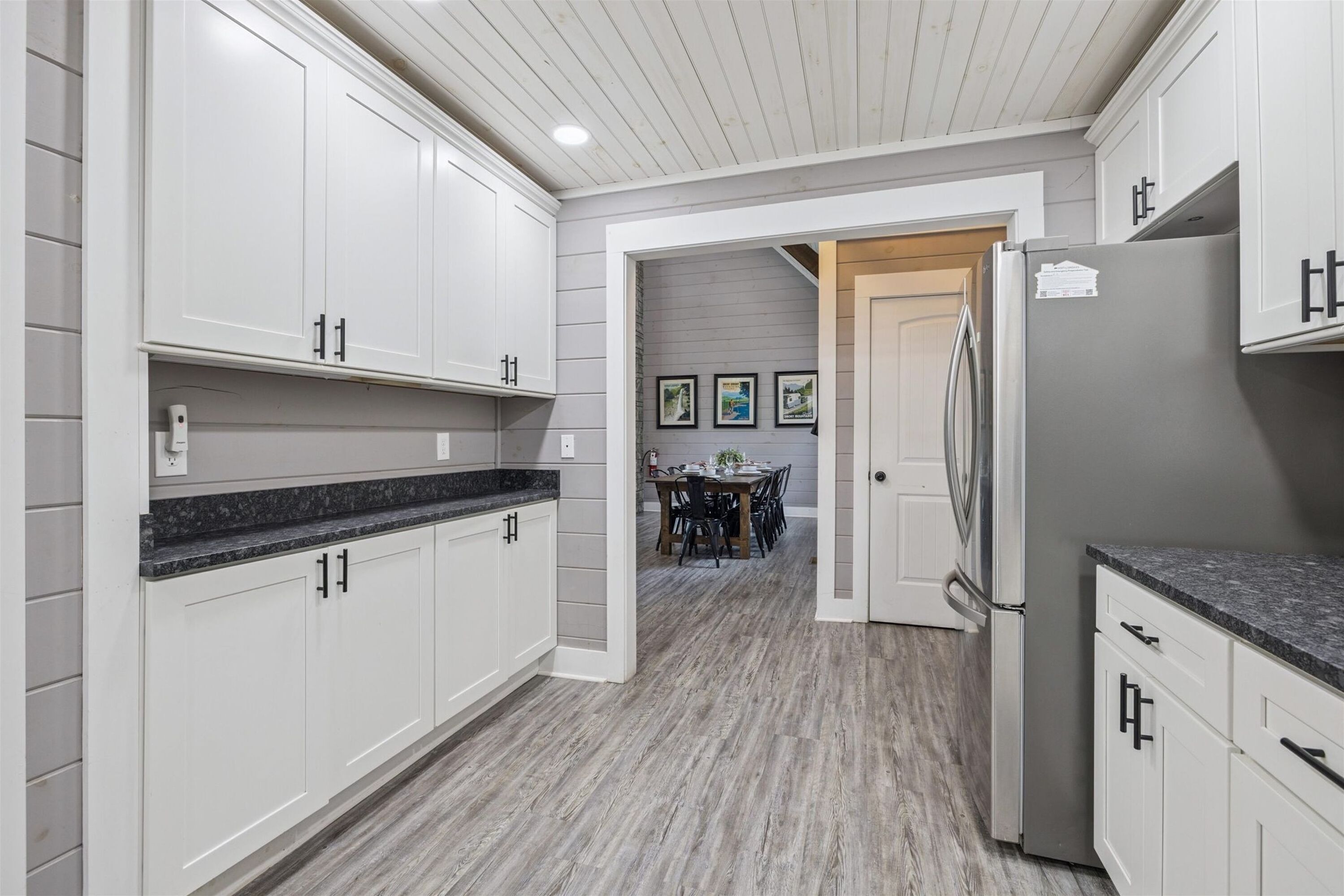 Una cocina moderna con armarios blancos, encimera de granito y refrigerador empotrado.