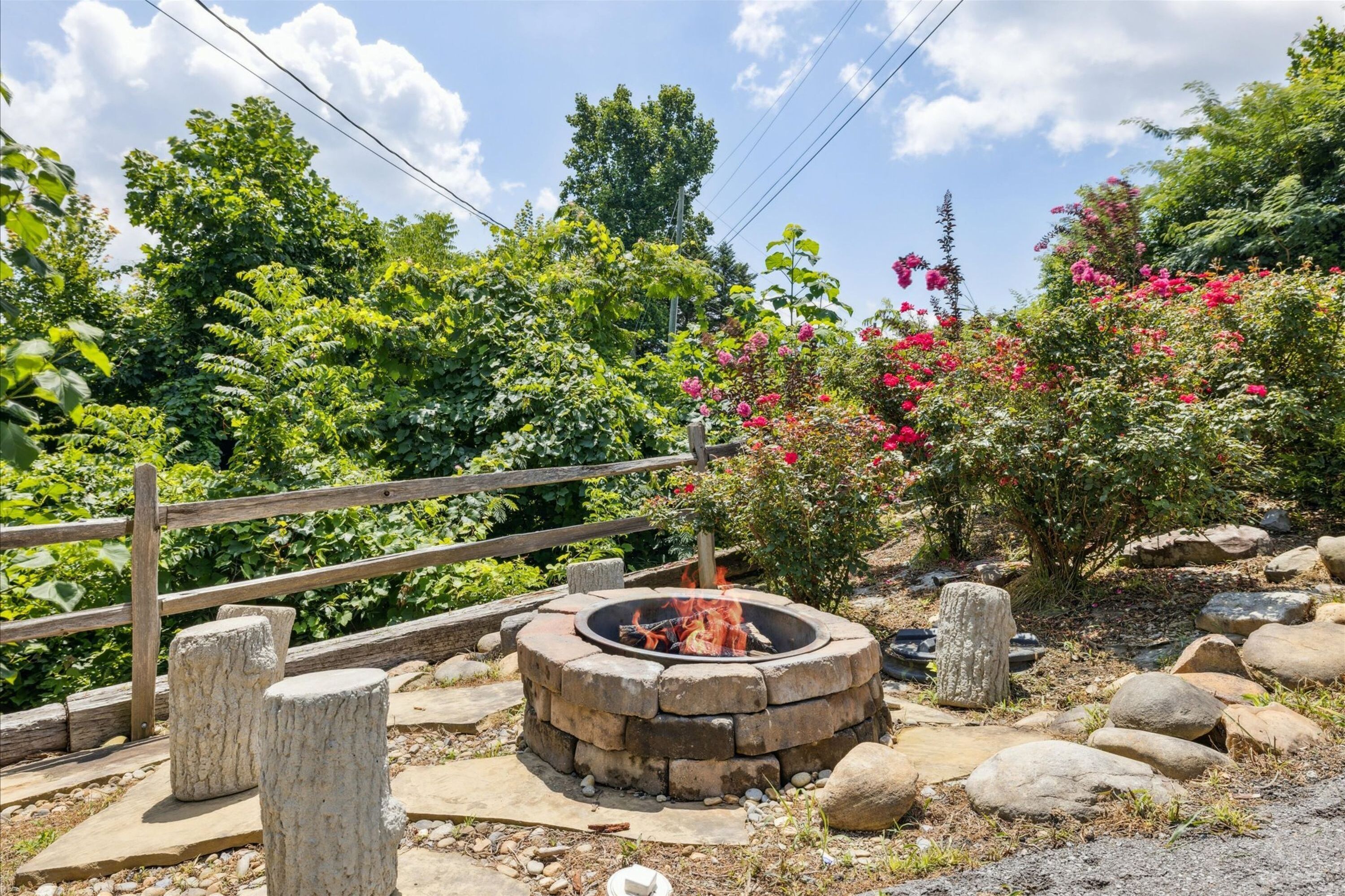A circular stone fire pit surrounded by rocks and a wooden fence.