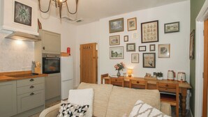 Una sala acogedora con sofá, mesa de comedor y cocina equipada con refrigerador y horno.