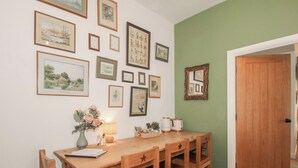 Un comedor con una mesa y sillas de madera, un jarrón de flores y cuadros en la pared.