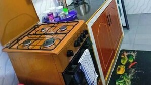 Een kleine keuken met een gasfornuis, magnetron en kastjes.