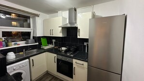 A modern kitchen with white cabinets, a stainless steel refrigerator, a built-in oven, and a washing machine.