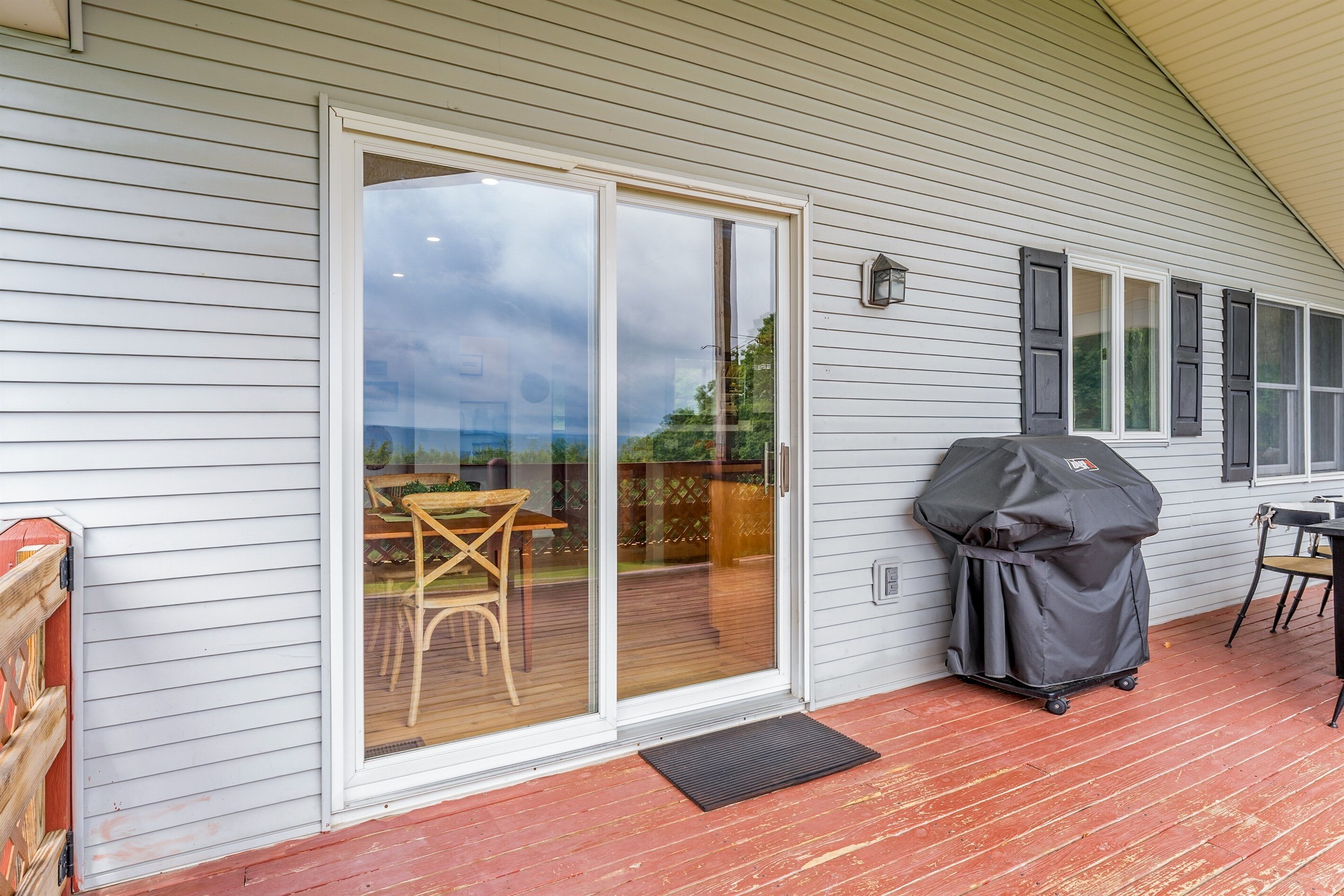A covered patio with a sliding glass door, a barbecue grill, and outdoor furniture.
